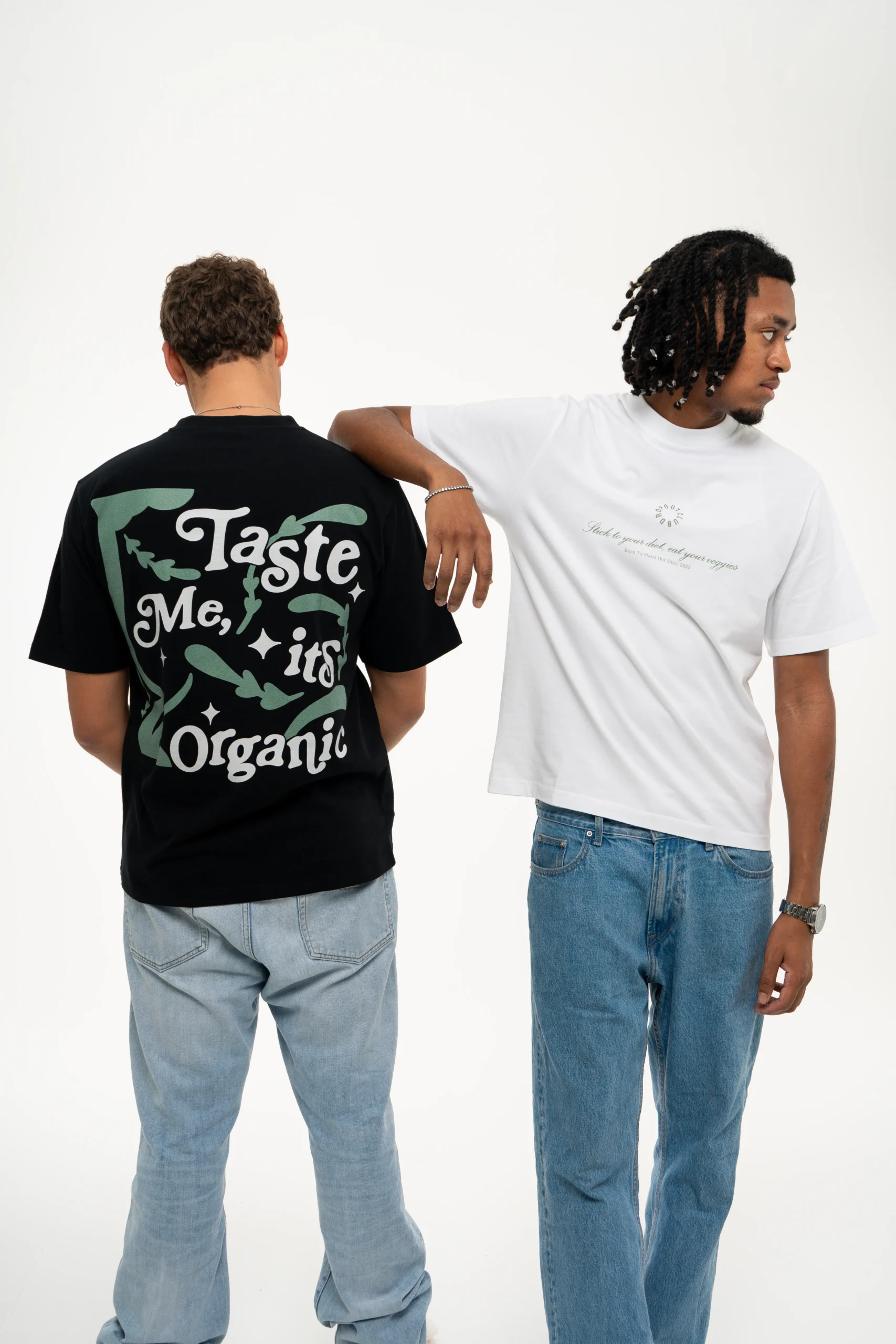 Photograph of two Dropout models, Flacko with his arm resting on Gustavo's shoulder wearing the Organic Taste White T-shirt from the front and Gustavo wearing the Organic Taste Black T-shirt from the back.