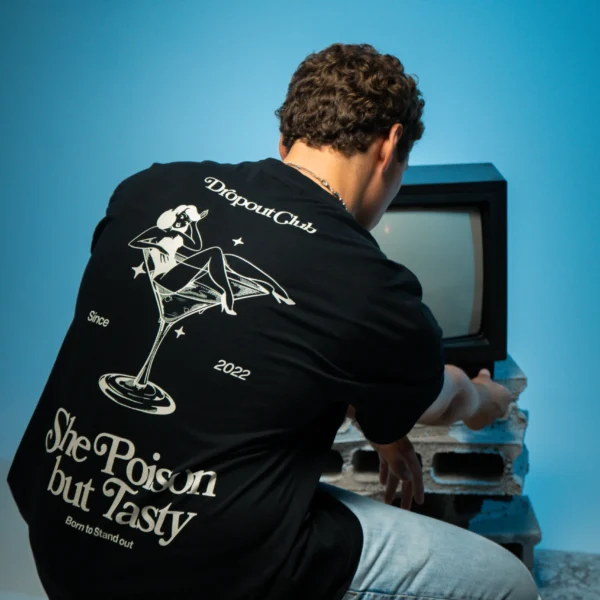 Gustavo wearing a Tasty Poison Black T-shirt by Dropout, turning up the volume on the television